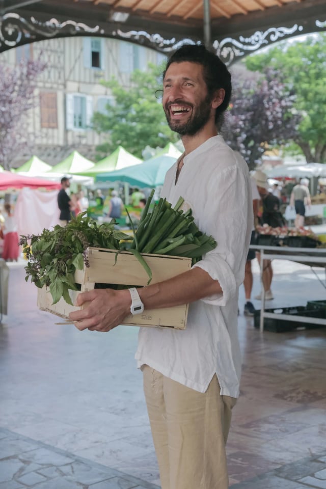 Virgile au marché, une cagette d'herbes dans les bras